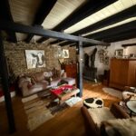 Spacious living room with wooden beams on the ceiling, wooden floors, and traditional windows in Kato Korakiana house