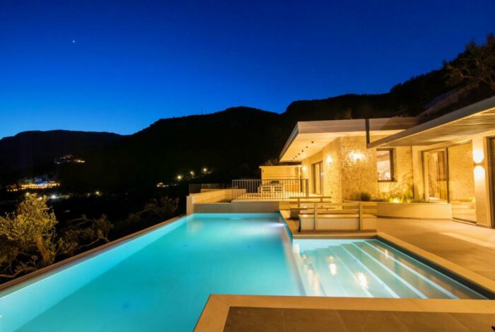 Tranquil night scene at Corfu villas with illuminated exteriors and sea view