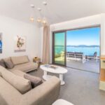 Open-plan living room with stone walls and sea-view windows in Katavolos villa