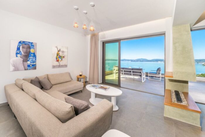 Open-plan living room with stone walls and sea-view windows in Katavolos villa