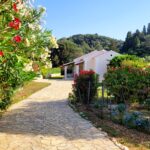 Private gated villa entrance with paved courtyard and mature greenery in Afionas