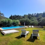 Outdoor relaxation area with pool and garden in peaceful Afionas property for sale