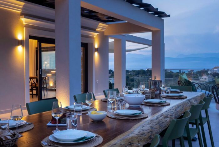 Peaceful evening setting with lit pergola, outdoor seating, and sea view