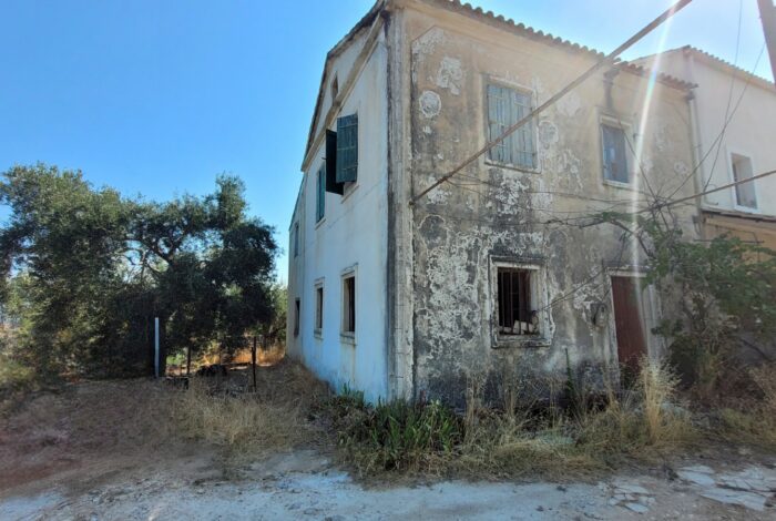 Exterior view of two-storey house with stone façade and tiled roof