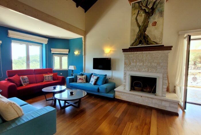 Living room with stone fireplace and wooden floors in Paxos villa