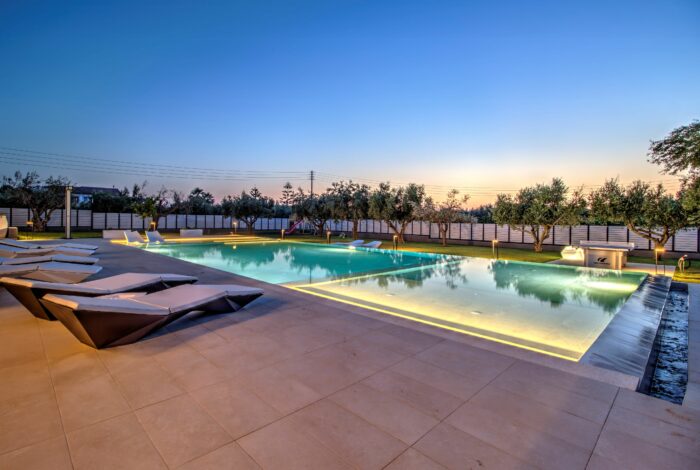 Large swimming pool surrounded by olive trees and sunbeds
